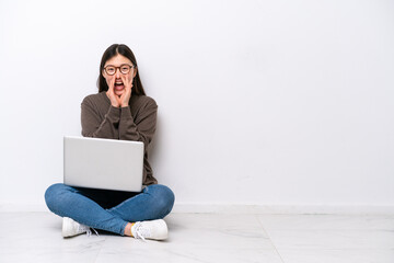 Young woman with a laptop sitting on the floor shouting and announcing something