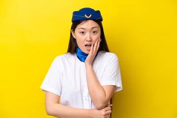 Airplane Chinese woman stewardess isolated on yellow background surprised and shocked while looking right