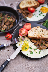 Close up view of the fried egg, mushrooms and bread on a frying pan