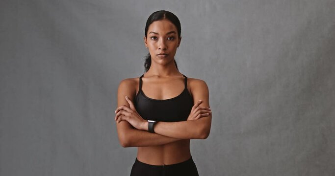 Female mixed race folding her arms with her fit bit watch looking serious.