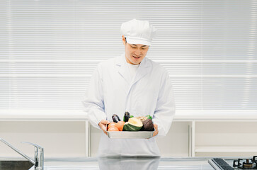 調理服を着た野菜を持つ男性（調理師・食品工場）
