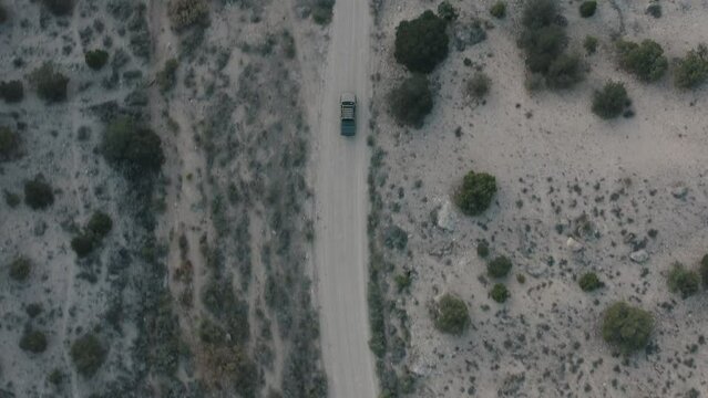 Drone shot of truck driving through desert. Drone shot of truck driving down dirt road. Vehicle driving on a dirt road. Driving in Utah mountains. Truck going through the mountains.