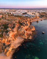 Aerial view at sunrise of the Lagos coast in Portugal. Cliffs and beaches in the foreground. and in...