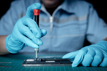 Technician repairing inside of mobile phone by little screwdriver and screws inside phone system is...