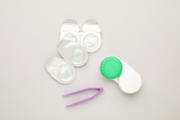 Packages with contact lenses, case and tweezers on white background, flat lay