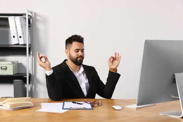 Young businessman meditating at workplace. Zen concept