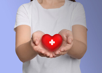 Woman holding red heart in hands on light background, closeup. Blood donation concept
