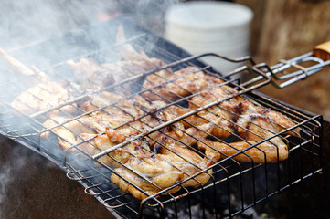 Tasty chicken wings cooking on barbecue grill, outdoors. Roasted chicken meat, closeup