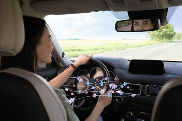 Woman enjoying driving car feeling flower scent from ventilation, closeup. Air freshener