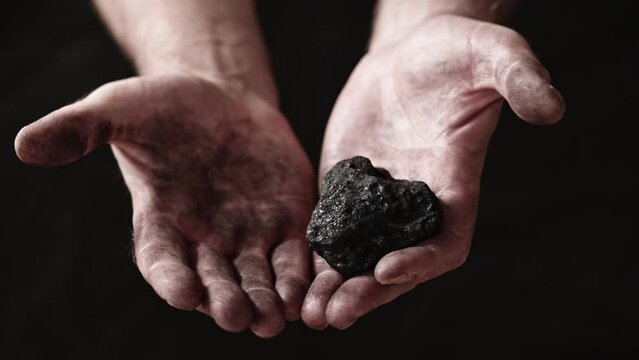 A miner shows the pieces and nuggets of coal in his hands.