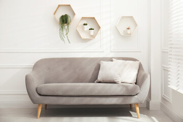 Honeycomb shaped shelves with decorative elements and houseplants on white wall in room