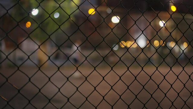 Through grid portrait of paddle tennis man playing on court outdoors. One caucasian padle player sportman hitting the ball. High quality 4k footage