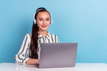 Friendly female helpline operator sitting desk using laptop consult client dispatch isolated blue...