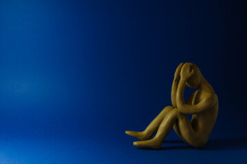 Plasticine figure of crying human on dark blue background. Space for text