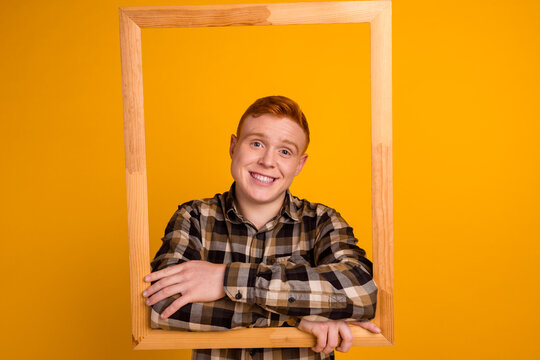 Portrait of funky cheerful man hold wooden frame make picture isolated over yellow color background