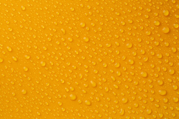 Water drops on orange background, top view