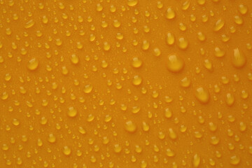 Water drops on orange background, top view