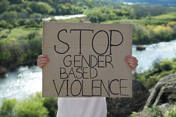 Woman holding sign with text Stop Gender Based Violence outdoors