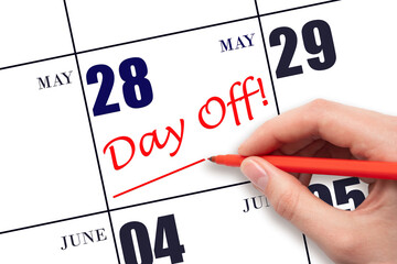 28th day of May. Hand writing text DAY OFF and drawing a line on calendar date 28 May. Vacation...
