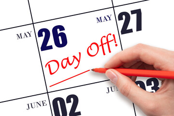 26th day of May. Hand writing text DAY OFF and drawing a line on calendar date 26 May. Vacation...