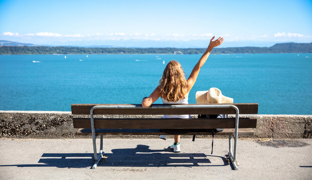 happy woman arms raised on a bench in front of sea