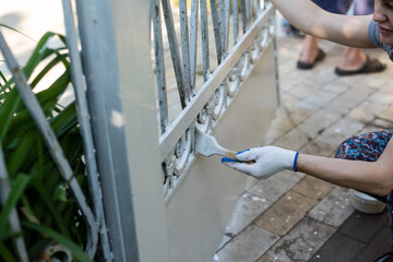 Hand wearing white gloves and painting with a paint brush.