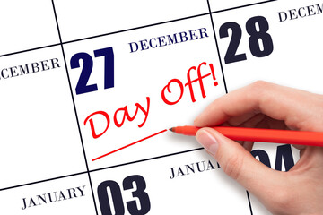 27th day of December. Hand writing text DAY OFF and drawing a line on calendar date 27 December. Vacation planning concept. Winter month, day of the year concept.