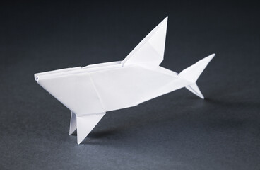 White paper shark origami isolated on a grey background