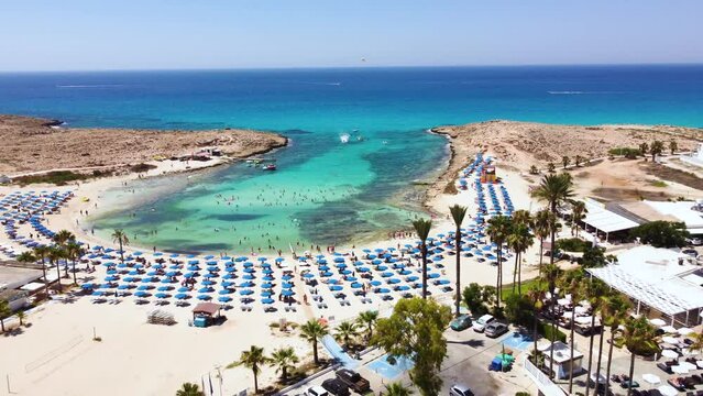 Aerial footage view of Vathia Gonia beach Ayia Napa, Famagusta, Cyprus from above. The landmark tourist attraction rocky bay with golden sand, sunbeds, sea restaurants in Agia Napa on summer holidays