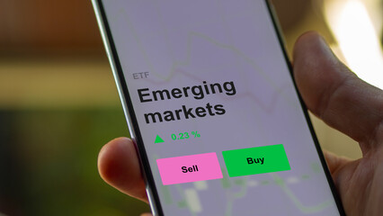 An investor's analizing the emerging markets etf fund on a screen. A phone shows the prices of bric, brics, BRIC, BRICS enterprises