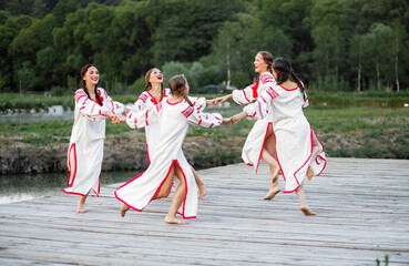 Fototapeta na wymiar Ukrainian girls in white dresses dance a stage dance in traditional style