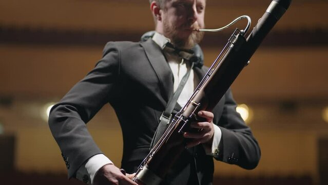 bassoonist in music hall, musician is playing bassoon on scene of theatre or concert hall