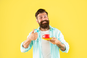 happy bearded guy drink morning coffee show thumb up on yellow background, coffee