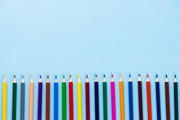 Wooden colored pencils on a blue background. Back to school concept. Horizontal orientation, top view, copy space.