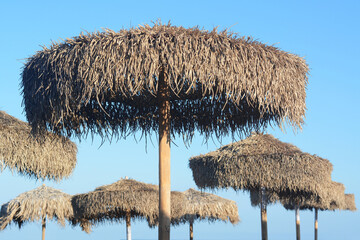 Plakat Beautiful straw beach umbrellas against blue sky