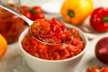 Spoon of delicious lecho over bowl, closeup
