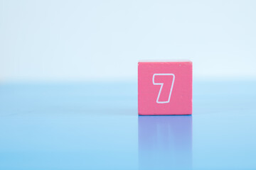Number 7 written on colorful wooden block isolated on background. 