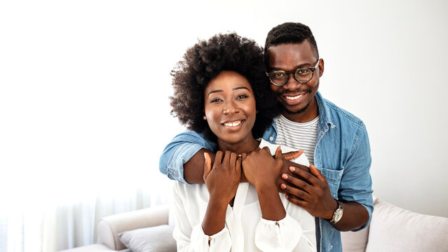 Portrait of happy african american couple hugging at home. Portrait of man with his woman looking at camera. Black mid adult couple. Meeting, love and date of young people