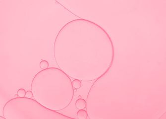 Water and oil droplets to creating circle and bubble shape on pink light effects background.