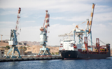 Large loading cranes in the international port of Israel. A ship is moored near the cranes, waiting...