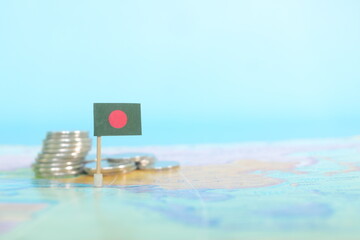 Selective focus of Bangladesh flag in blurry world map with coins. Bangladesh economy and wealth concept.	