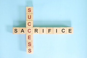 Sacrifice for success concept. Wooden blocks crossword puzzle with words sacrifice and success.