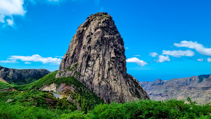 Scenic view on massive volcanic rock formation Roque de Agando in Garajonay National Park on La Gomera, Canary Islands, Spain, Europe. Lava cone of an old volcano. Hiking trail on sunny day in summer