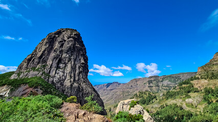 Scenic view on massive volcanic rock formation Roque de Agando in Garajonay National Park on La Gomera, Canary Islands, Spain, Europe. Lava cone of an old volcano. Hiking trail on sunny day in summer