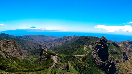 Fototapeta na wymiar Scenic mountain road with view on massive volcanic rock formation Roque de Agando in Garajonay National Park on La Gomera, Canary Islands, Spain, Europe. View seen from lookout Mirador Morro de Agando