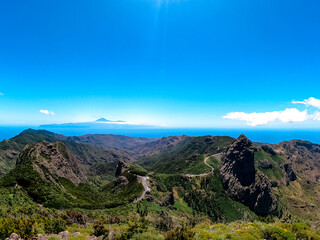 Scenic mountain road with view on massive volcanic rock formation Roque de Agando in Garajonay National Park on La Gomera, Canary Islands, Spain, Europe. View seen from lookout Mirador Morro de Agando