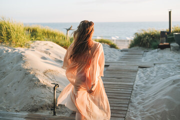 Young woman with long blonde hair in outdoor spa center against the background of sunset sea - obrazy, fototapety, plakaty