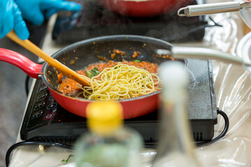 Cooking spaghetti concept. Pasta in the pan. Cooking Fresco Pasta. Italian cuisine, Cooked Italian spaghetti being put into hot bolognese sauce in the pan