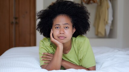 Close-up happy afro asian woman with afro hairstyle lies on the bed in the hotel in quarantine....