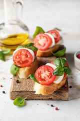 Bruschetta with tomatoes, mozzarella and basil on wooden board with ingredients